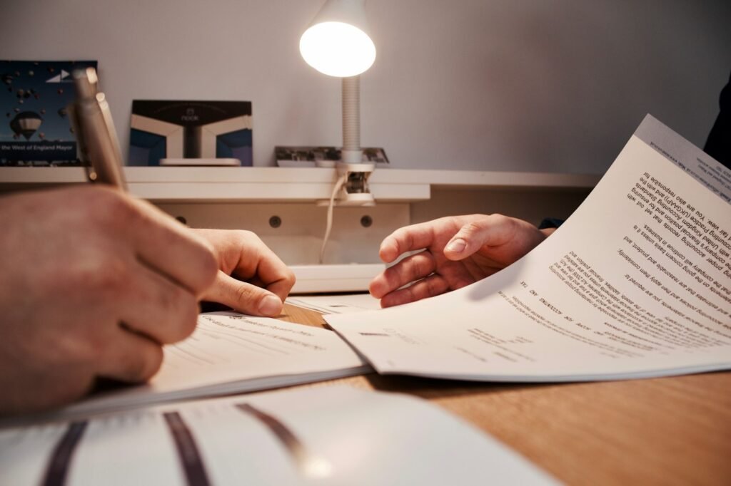 Hands reviewing and signing paperwork at a desk.