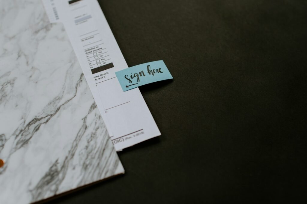 Document with a sign-here note beside a dark folder.