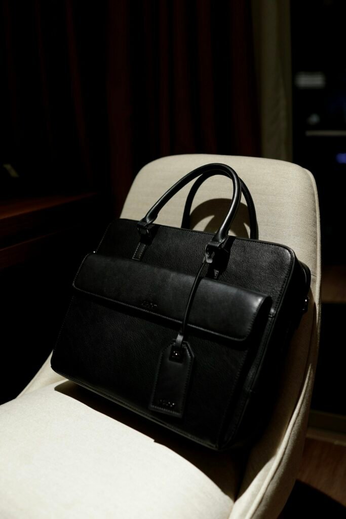 A black leather document bag on a cream chair.